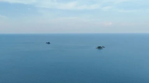 Aerial view of two small rocky islands surrounded by calm blue sea and open sky Stock Footage 310820787