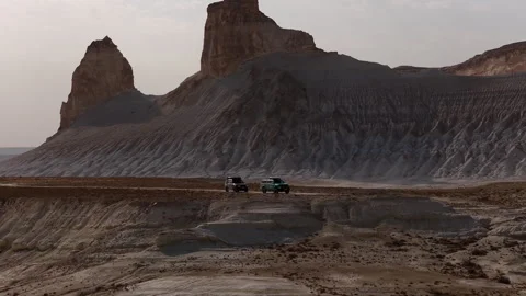 Aerial view of two suvs driving in a dramatic desert canyon landscape of Bozjyra Stock Footage 322047467