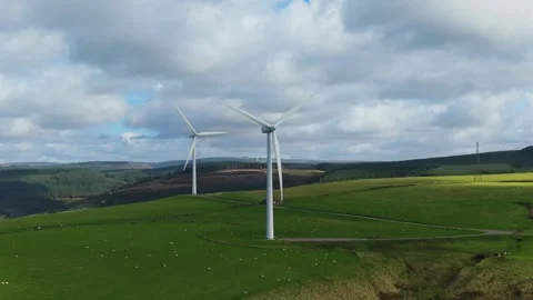 Aerial View of Two Wind Turbines Spinning on Hilltop with Rolling Hills in Vídeos de archivo 348149148