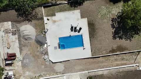 Aerial view of an unfinished backyard pool with a blue protective cover and Stock Footage 301786215