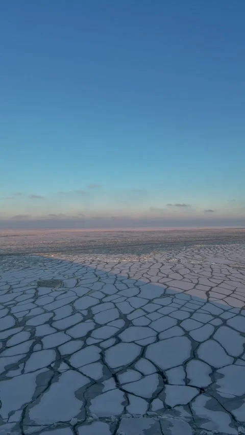 Aerial view of a unique mosaic pattern on a frozen sea under a blue sky. Stock Footage 337783015