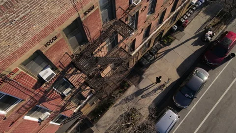 Aerial view of an unknown pedestrian walking down a Brooklyn sidewalk at sunrise Stock Footage 237211273
