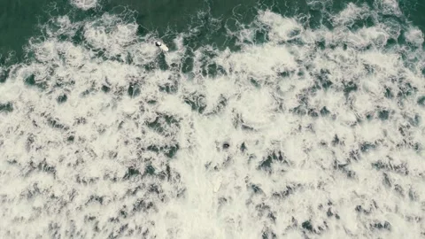 Aerial view of an unrecognizable surfer navigating the foamy, turbulent surf 스톡 동영상 329717686
