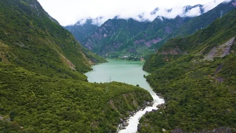 Aerial view of upstream thin stream converge into big lake green mountain forest Video stock 337926748
