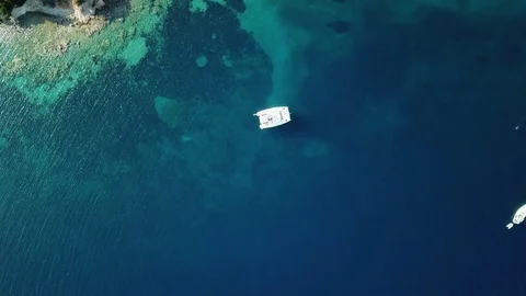 Aerial view, upward pull back, sailboats anchored in a lonely bay with blue sea Stock Footage 96296433