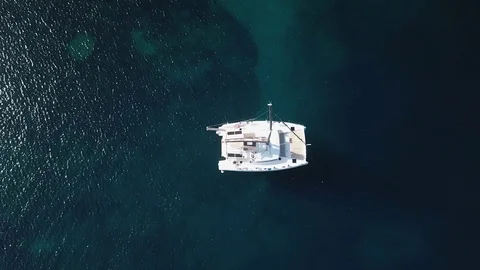 Aerial view, upward pull back Catamaran sailboat anchored on a dark blue sea Stock Footage 96297522