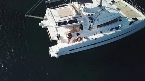 Aerial view, upward pull back Catamaran sailboat anchored on a dark blue sea Stock Footage 96297546