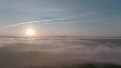 Aerial View Of A Valley Covered With Dense Mist Contrails In Sky At Sunset Stock Footage 333199582