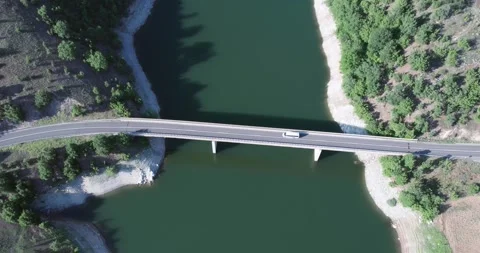 Aerial view of a van mini bus drive on a bridge crossing over a calm river or Stock Footage 277650361