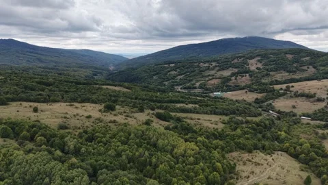 Aerial view of vast green rolling hills and meadows under a cloudy horizon Stock Footage 345608980