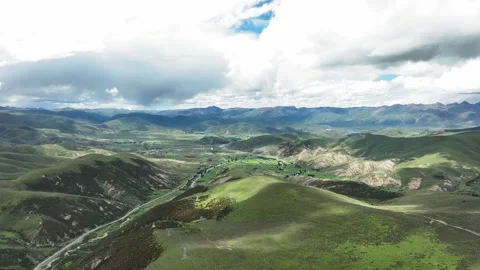 Aerial view of vast undulating green plateau basin between layered distant Stock Footage 336698801