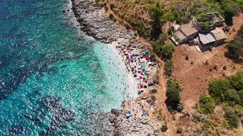 Aerial view of a vibrant beach scene with colorful umbrellas, sunbathers Stock Footage 345153997