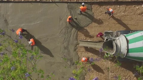 Aerial View: A vibrant construction site shows workers pouring concrete into the Stock Footage 296084024