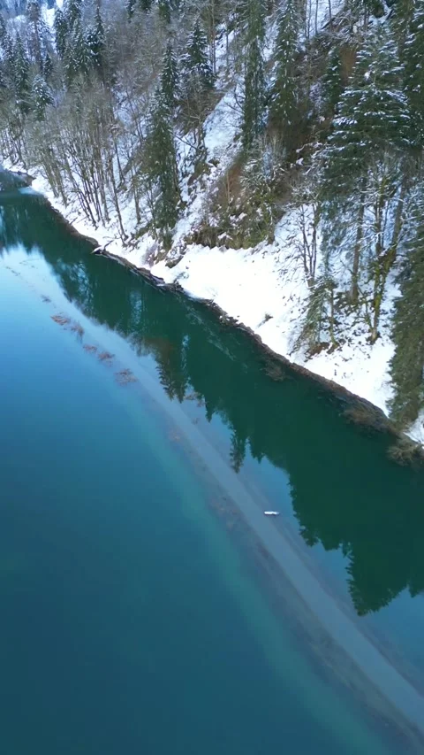 Aerial view of a vibrant deep green river flowing through winter landscape pine 스톡 동영상 334118012