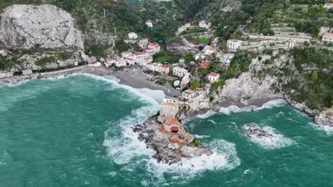 Aerial view of the vibrant Erchie beach with its historic coastal tower, set Stock Footage 325389337