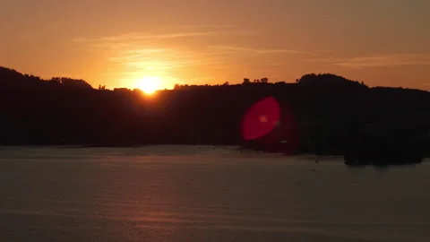 Aerial view of vibrant sunset hiding behind alpine village on hill horizon Видео 345605830