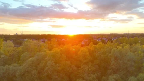 Aerial view of a vibrant sunset over a rural landscape, showcasing trees and Vidéo 334032626
