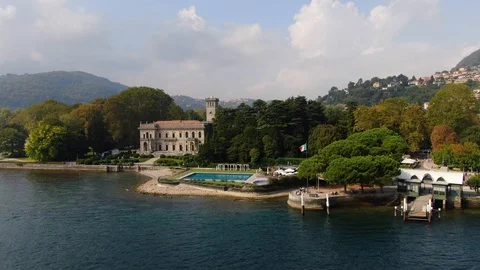 Aerial view of Villa Erba, pool, pier, motor boat sailing on Lake Como Stock Footage 129633446