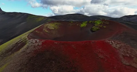 Aerial view of a vivid red volcanic crater with green moss patches and dark Stock Footage 332393034