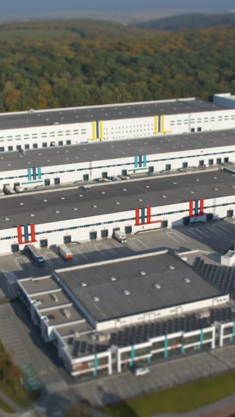 Aerial view of a warehouse complex amidst lush greenery, showcasing logistics Stock Footage 328913853
