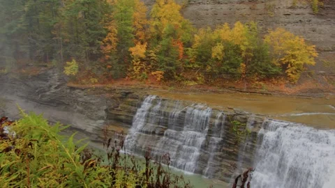 Aerial view of a waterfall cascading into a forest creek in Letchworth State Par Stock Footage 304223905