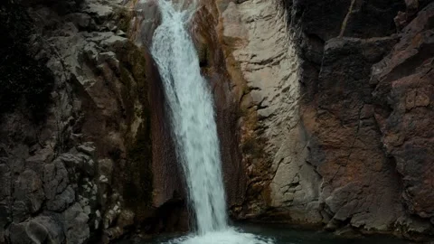 Aerial view of a waterfall flowing into the river in between the mountains Stock Footage 172107035