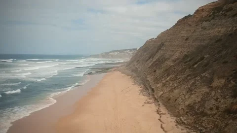 Aerial view of waves on a beautiful sandy ocean beach and cliff Stock Footage 134835342