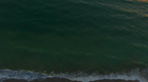 Aerial view waves break on white sand beach at sunset, land meets sea Stock Footage 68917046