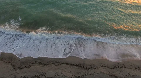 Aerial view waves break on white sand beach at sunset, land meets sea Stock Footage 68917314