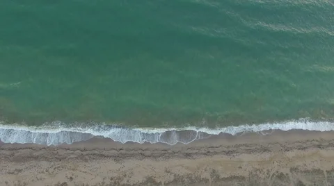 Aerial view waves break on white sand beach at sunset, land meets sea Stock Footage 68919044