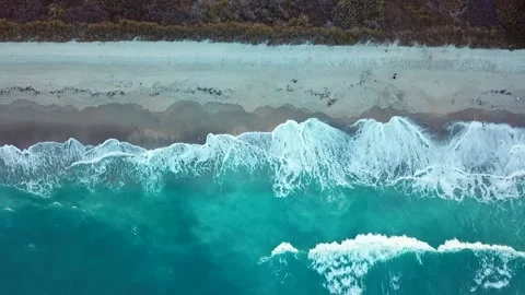 Aerial view waves break on white sand beach, land meets sea Stock Footage 237952059