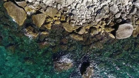 Aerial view of waves breaking against coastline rocks Stock Footage 83371286
