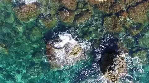 Aerial view of waves breaking against coastline rocks Stock Footage 83371759