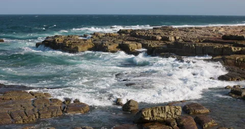 Aerial view of waves breaking on the rocks of the rugged, rocky beach coastline Stock Footage 153757758