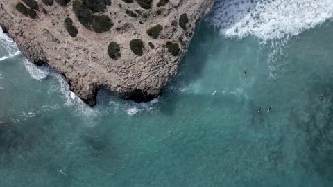Aerial view waves crash on rocks. Surfers ride the waves. Rough sea. Super slow  库存影片 253183968