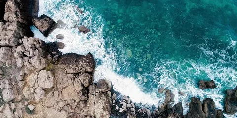 Aerial view of waves crashing on cliffs by a blue sea Stock Footage 230418733