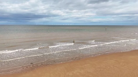 Aerial view of waves at Crosby Beach with offshore wind farm background Stock Footage 337768240