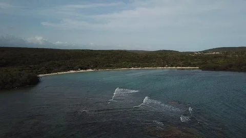 AERIAL: View of the waves entering the bay of a paradisiacal island, with Stock Footage 99562624