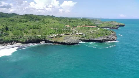 Aerial view of the waves hitting the rocks on the edge of a green cliff. na.. Stock Footage 239618196