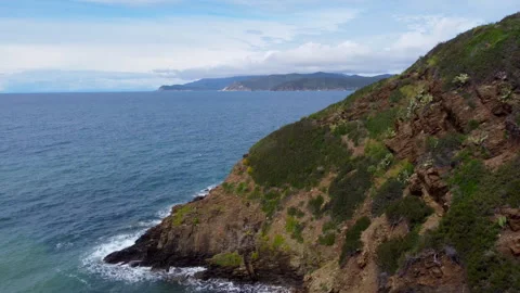 Aerial view of waves hitting rocks on a green island Stock Footage 322996647