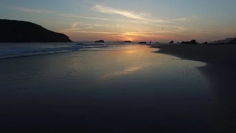 Aerial View of Waves Lapping On The Shore At Sunset with Silhouetted Person Stock Footage 71160739