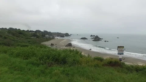 Aerial View of Waves Lapping Shore Along Green Coastal Town Video stock 71162720