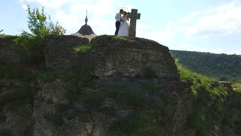 Aerial view of wedding couple standing on a cliff kissing Stock Footage 71480004
