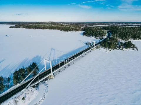 Aerial view of white cable-stayed bridge with snow lakes ? green woods in Fin Stock Photos
