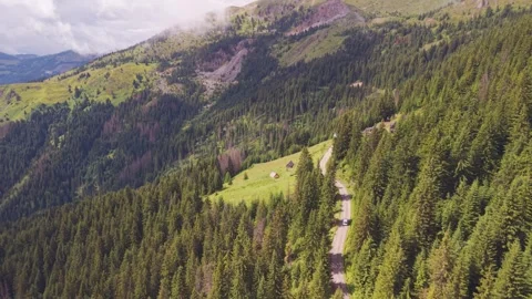 Aerial view of a white camper van driving along a serpentine mountain road past Stock Footage 342324311