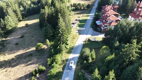 Aerial View of White Camper Van Driving past Solar Panels and Mountain Resort in 動画素材 343839229