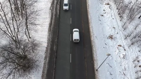 Aerial view of white car driving along a snow-covered road. Automobile movement Stockbeeldmateriaal 335883509