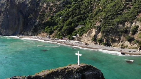 Aerial view white cross stands on rock top against beach Video stock 103181586