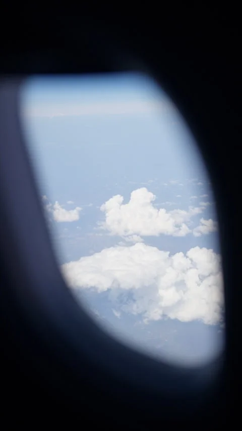 Aerial view of white, fluffy clouds above fields seen from an airplane window. Stock Footage 314111964