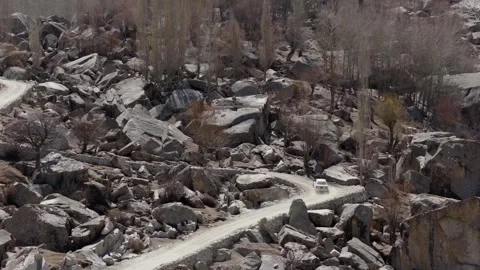 Aerial view of a white SUV navigating a winding dirt road through a rugged Stock-Footage 314457276